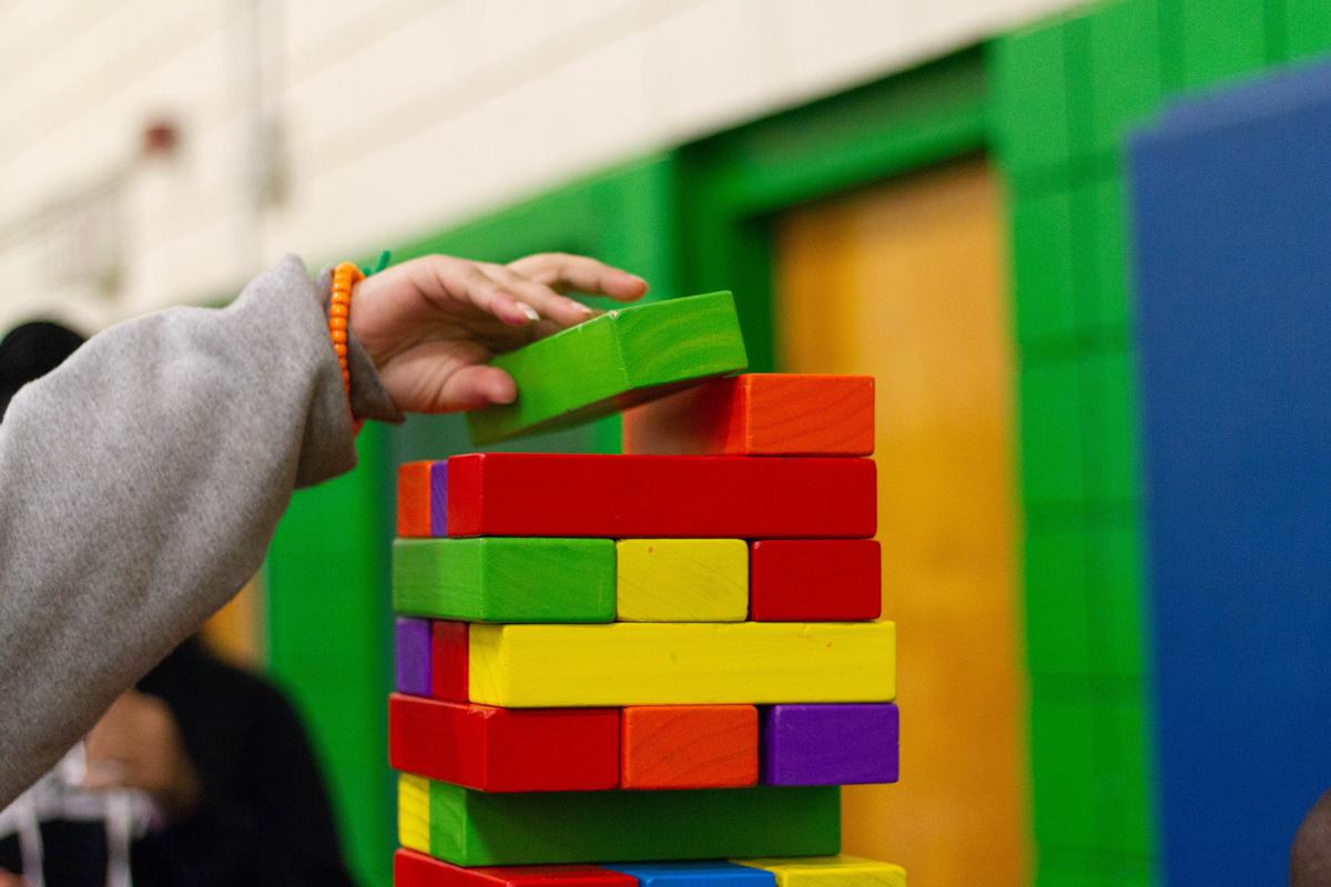 A person building a tower with blocks, one block at a time.