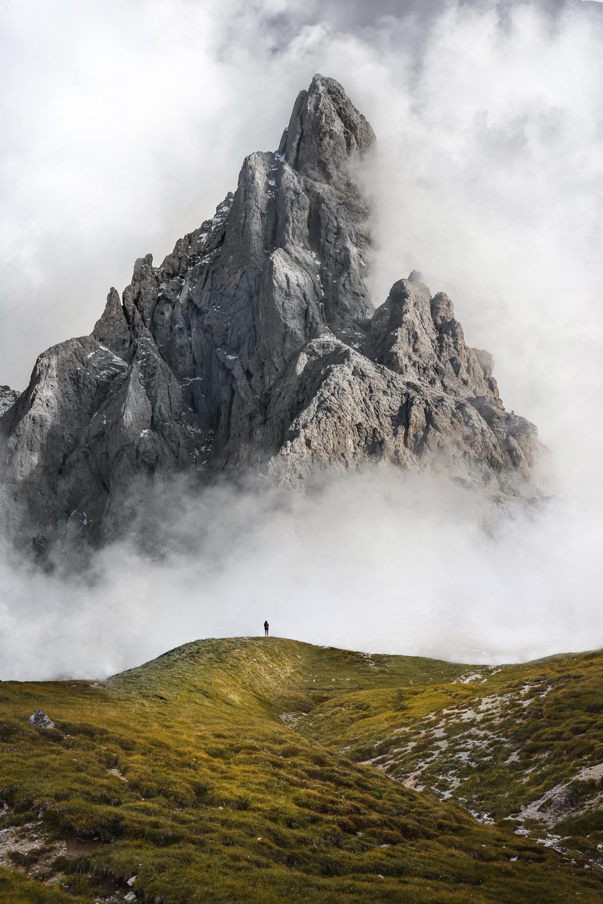 A person sitting on a rock with countless mountains in the background, symbolizing the strength to face life challenges with emotional resilience.
