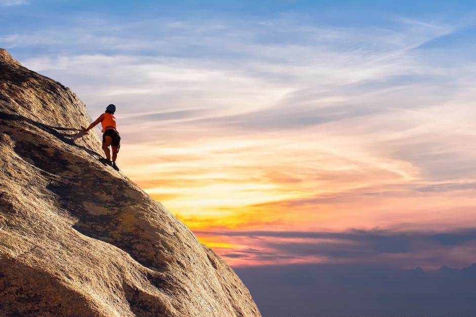 A person climbing a steep mountain using their hands and feet, symbolizing the strength and perseverance needed to overcome obstacles.