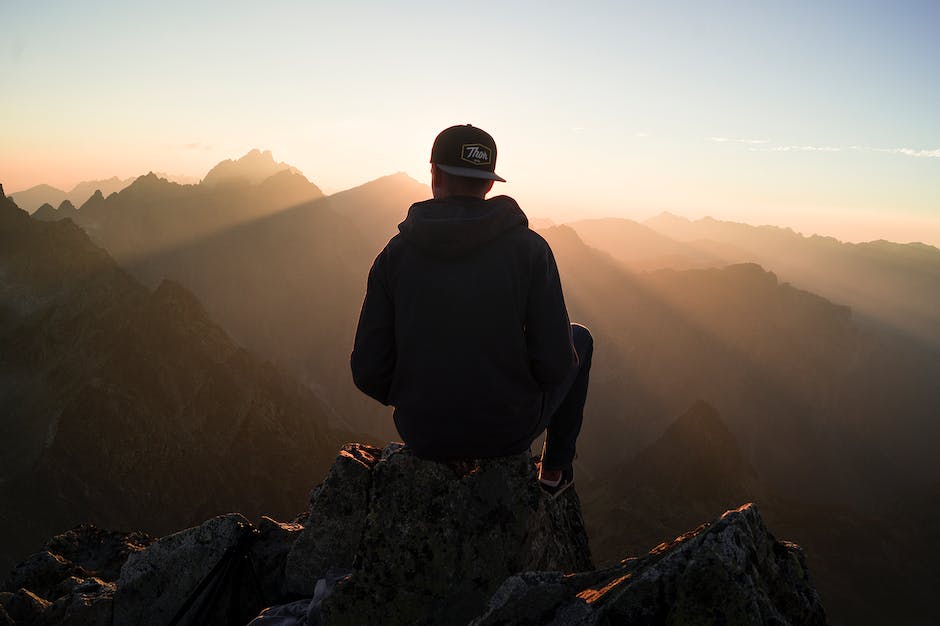A person standing at the top of a mountain with arms raised to signify personal growth and accomplishment.
