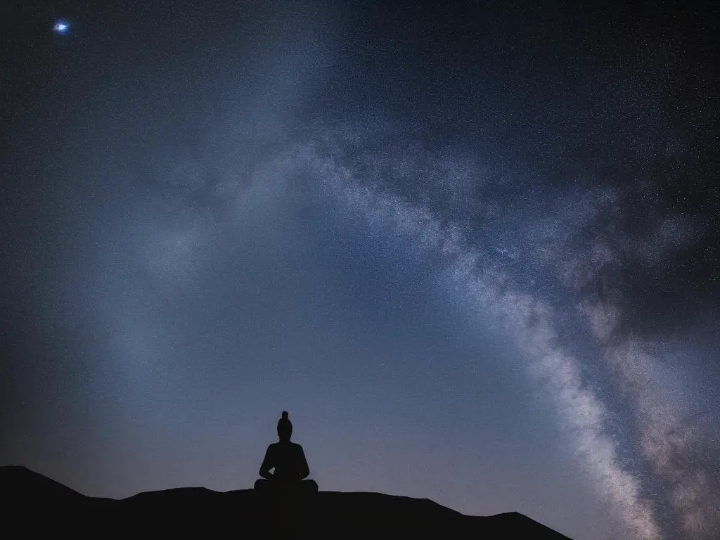 A silhouette of a person sitting in a meditation pose, surrounded by stars, representing spiritual growth